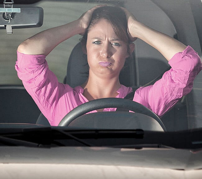 Frustrated person holding their head in the car